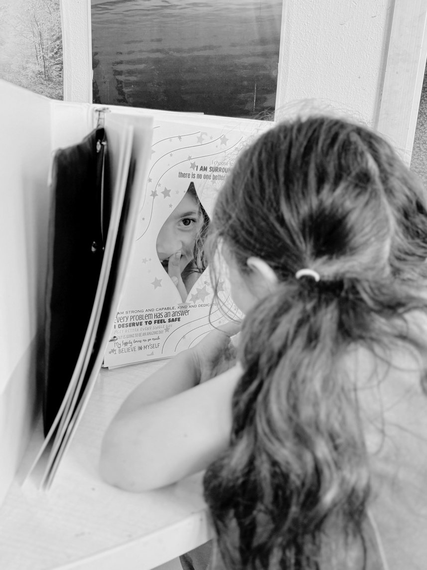 A student seen from behind, reading a page in her open SEL binder.