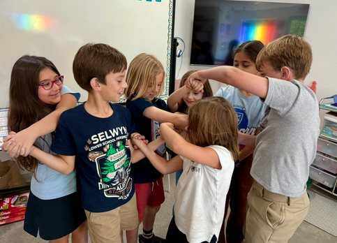 A line of Selwyn students with their arms linked over each other's shoulders, laughing.